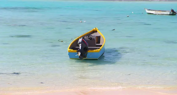 Blue amd yellow fishing boat gently resting on the tranquil sea