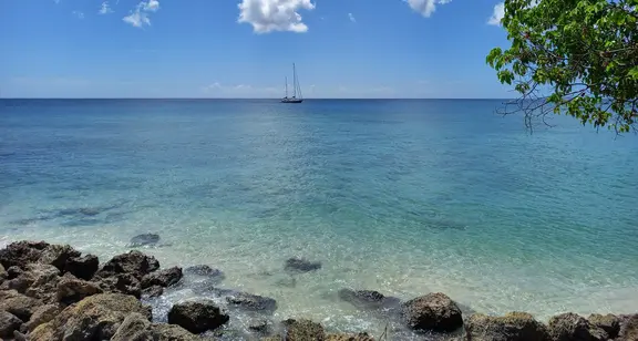 Ocean on a bright sunny day with a yacht in the distance