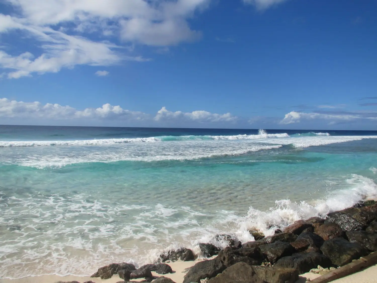 Sheltered bay with gentle waves breaking on the boulders lining the boardwalk