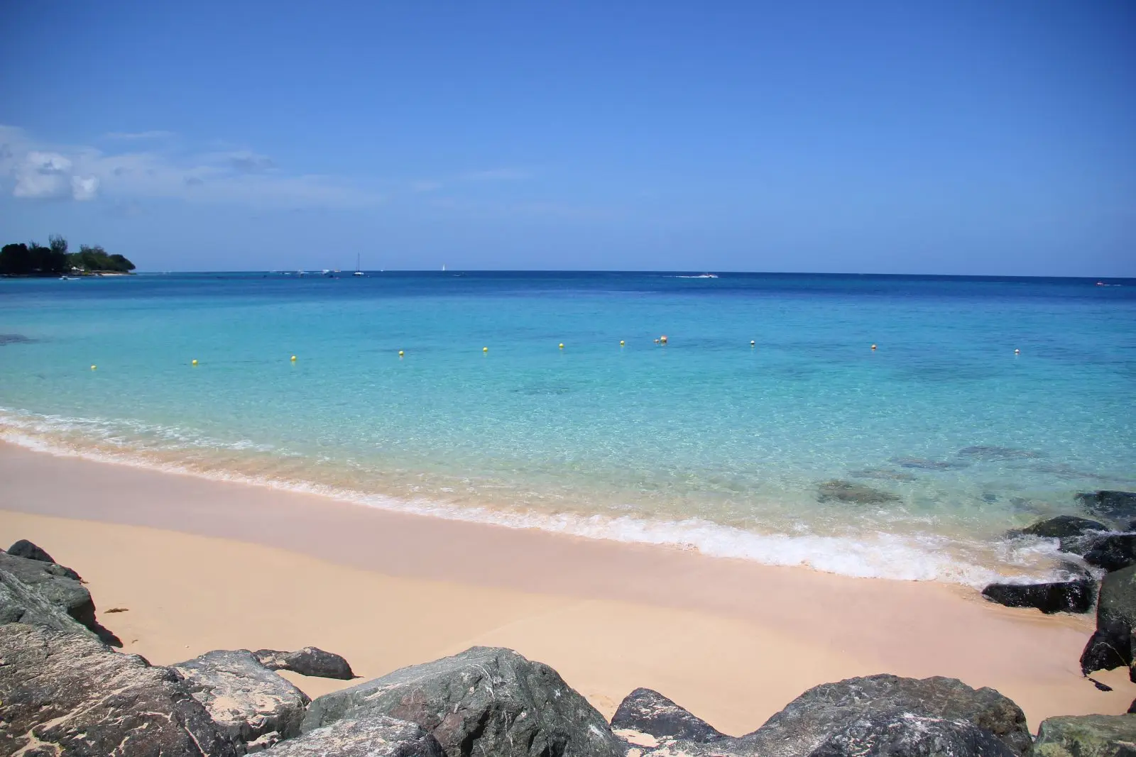 Turquoise waters gently break on soft white sand shores under a brilliant blue sky