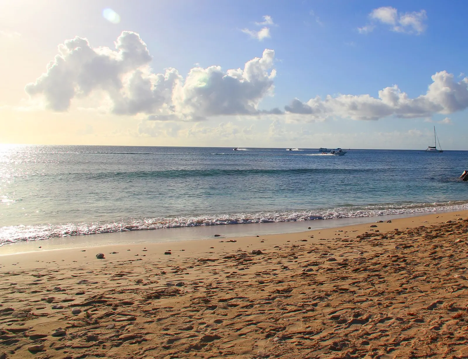 Wide sandy beach with tranquil waters lapping the shore on a sunny day